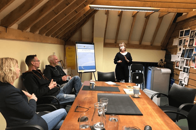 A person speaking to 3 other people in a meeting