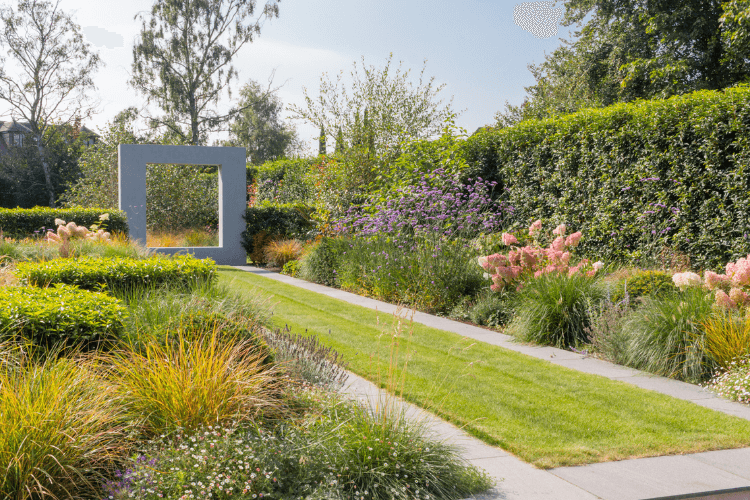 small garden vista leading to a square stone structure bordered by planted beds