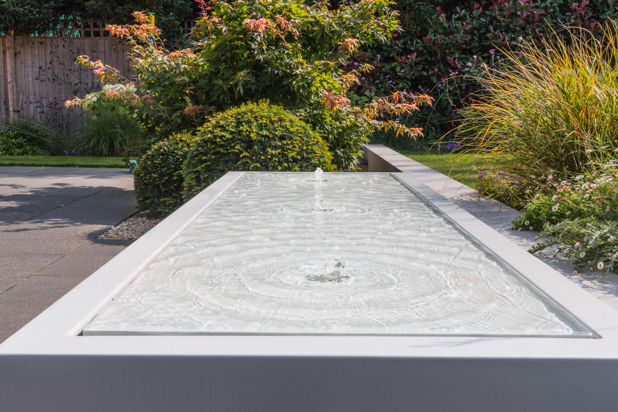 A watre feature consisting of three small fountains on a flat plane of stone