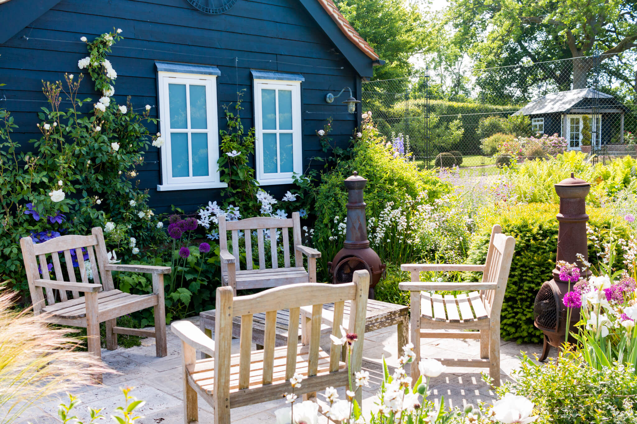 Four wooden benches and a table near a couple of wood-burning stoves